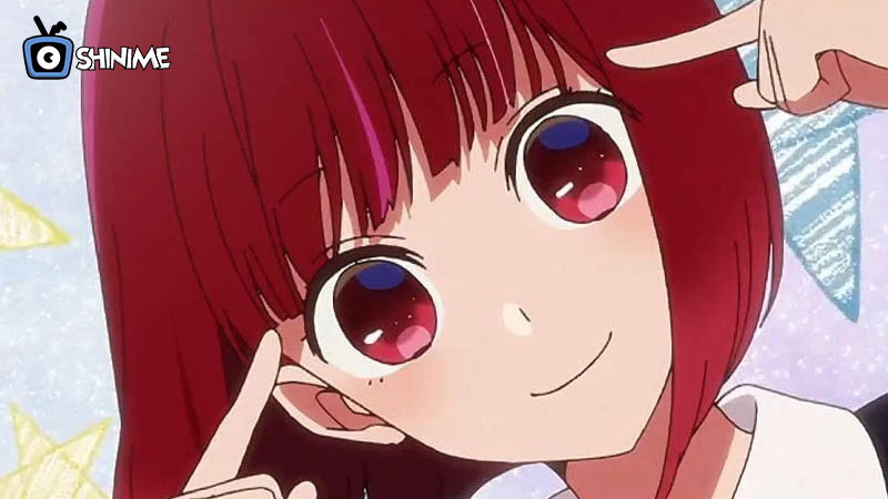 Most popular anime characters 2024: Kana Arima pointing at cheeks with big pink eyes and short red hair