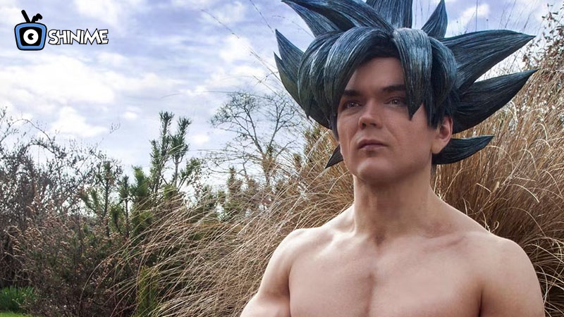 Cosplayer musculoso de Goku con peinado Super Saiyan Blue y gi naranja, ícono top para cosplay anime.